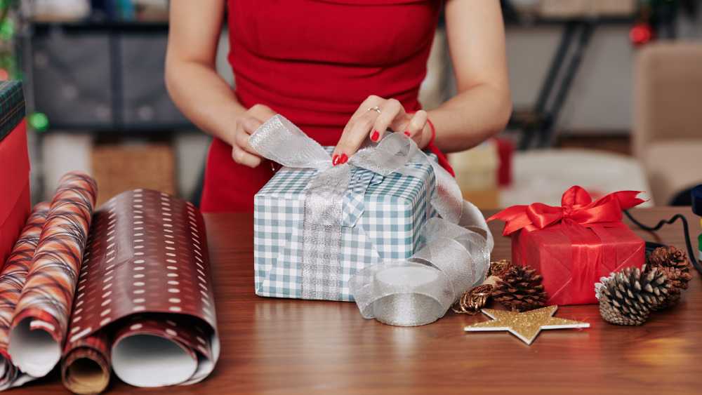 Girl wrapping gift with ribbon